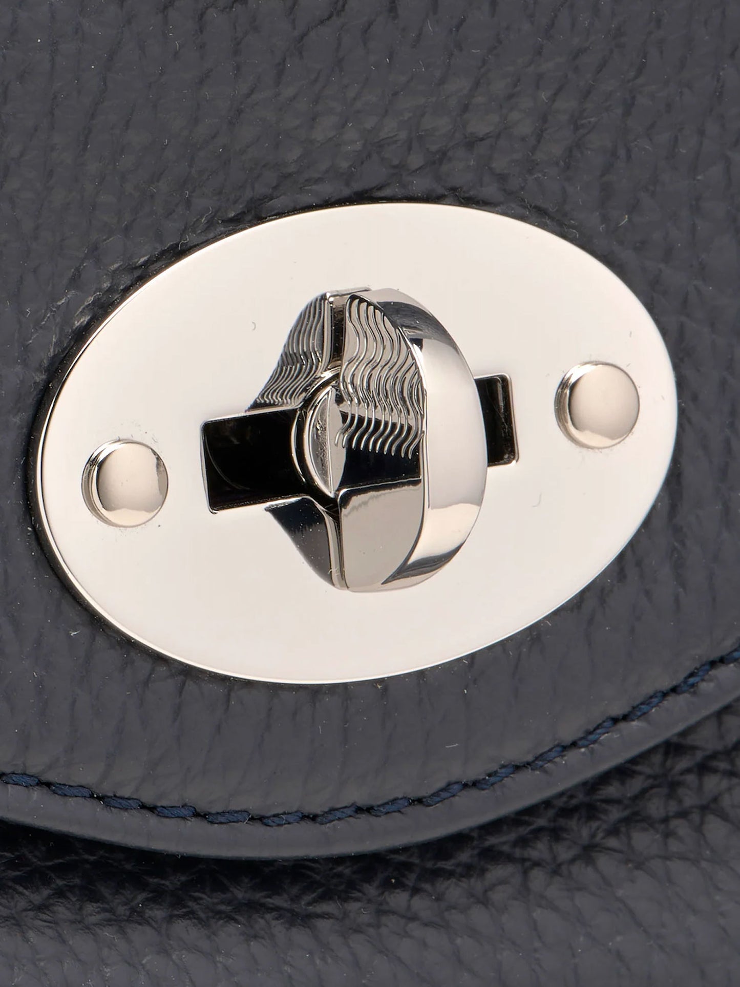 Close-up of a silver lock mechanism on a navy leather surface