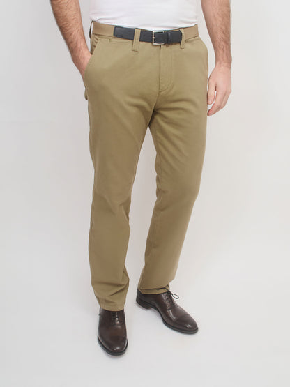Person wearing beige pants with a white shirt and brown shoes on a light gray background
