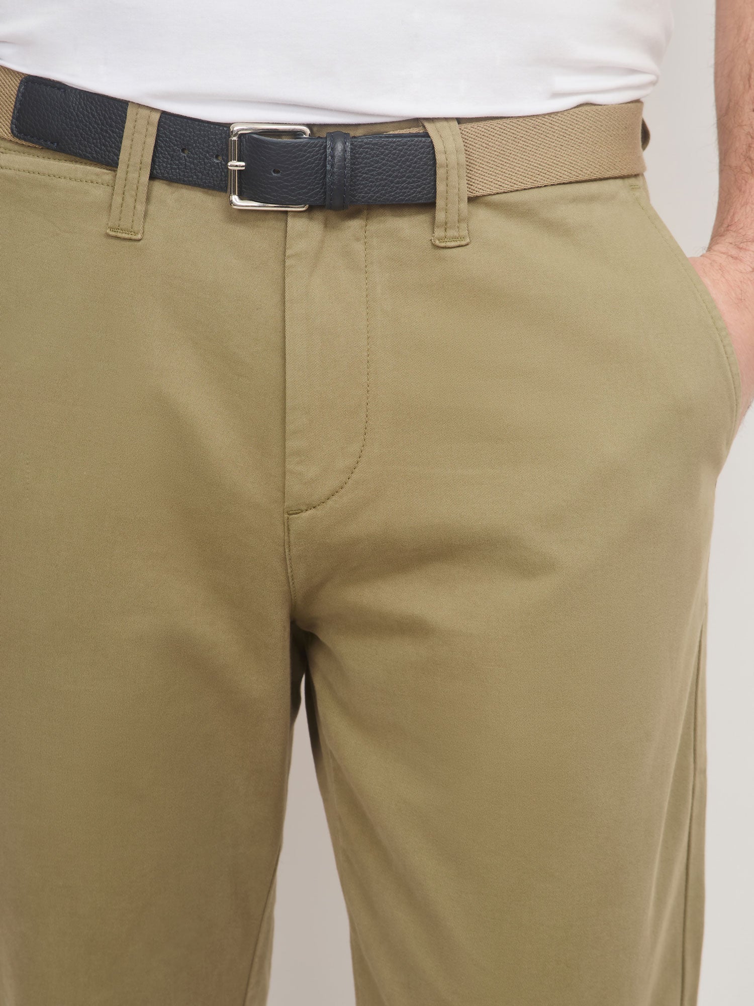 Beige pants with a black belt on a plain background