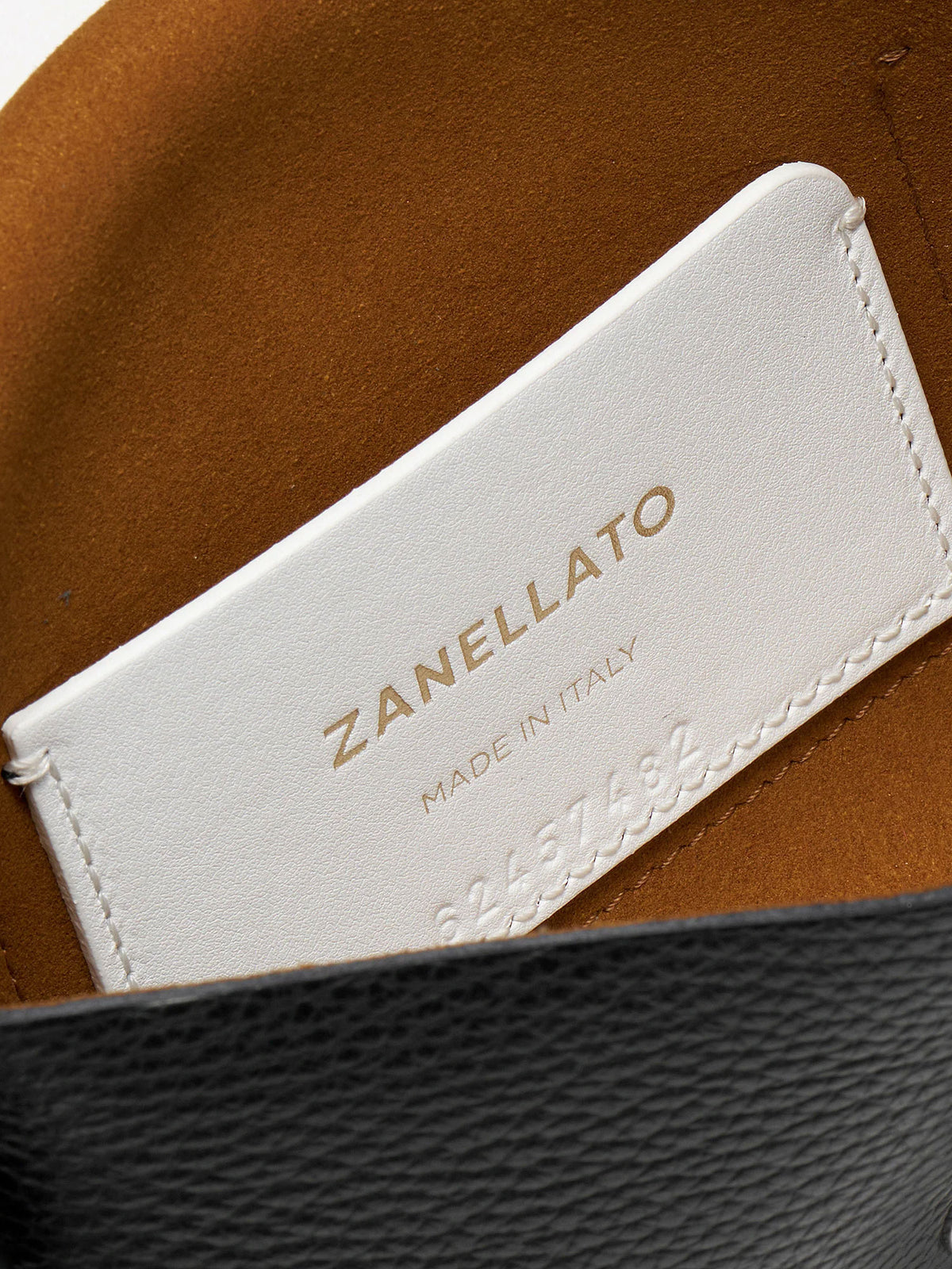 Close-up of a white leather interior label stitched onto a brown leather hat, with the brand name ZANELLATO and 'MADE IN ITALY' embossed on the label.