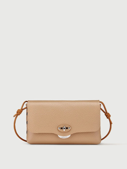 A beige pebbled leather crossbody bag with a matching adjustable leather strap and a silver-tone turn-lock closure on the front flap, shown against a light gray background.