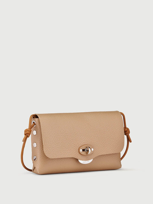 A small tan pebbled leather crossbody bag with a flap closure, silver-tone hardware, and a thin brown leather strap, shown on a light gray background.