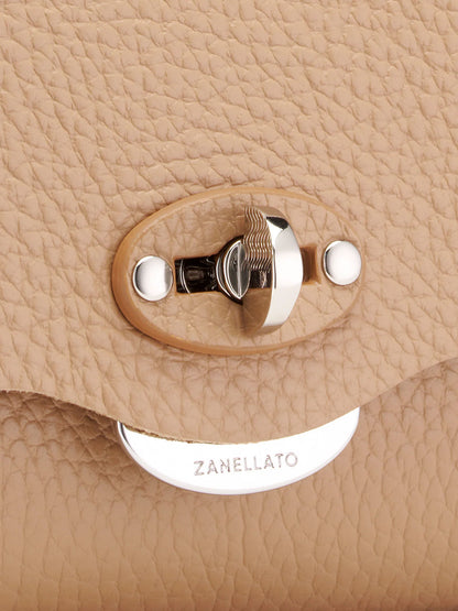 Close-up of a beige handbag with a metal clasp and 'Zanellato' branding.