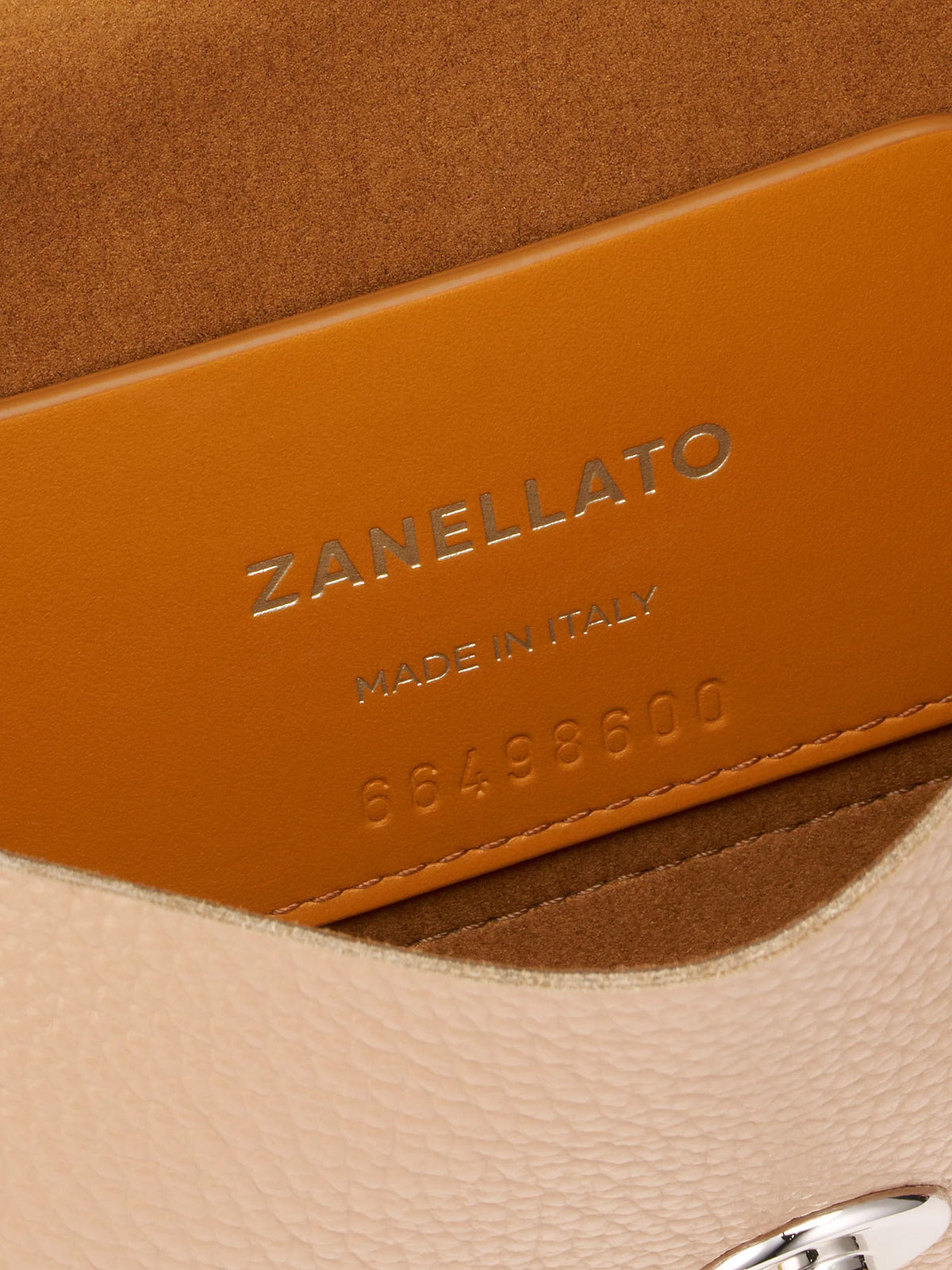 Close-up detail of a Zanellato leather bag showing a warm tan leather interior panel with silver embossed branding and a light beige textured exterior.