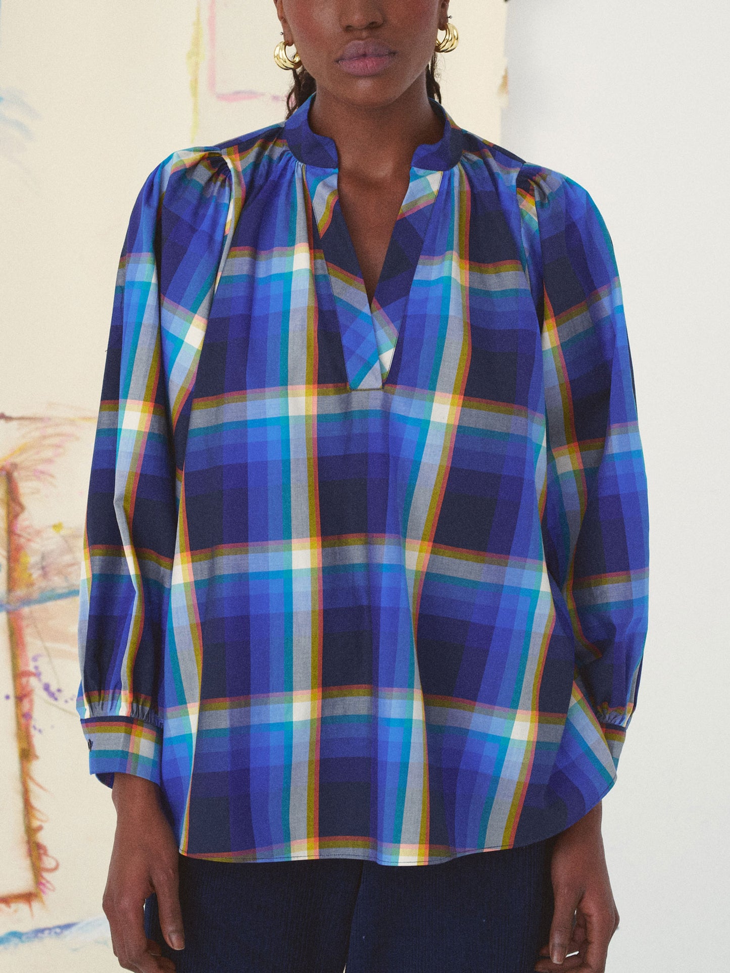 Person wearing a blue plaid shirt against a neutral background