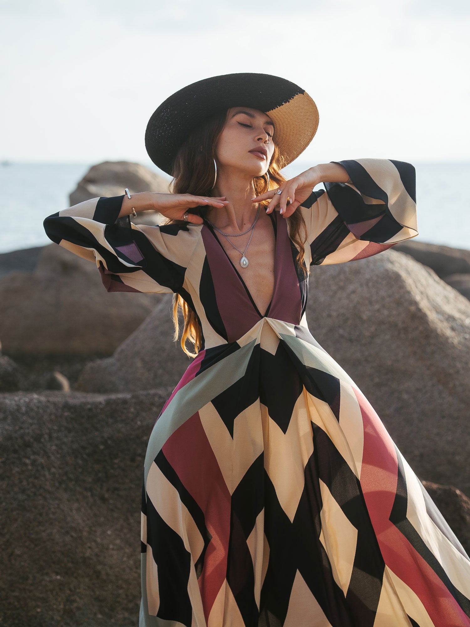 Woman in a colorful dress and hat posing in a desert landscape
