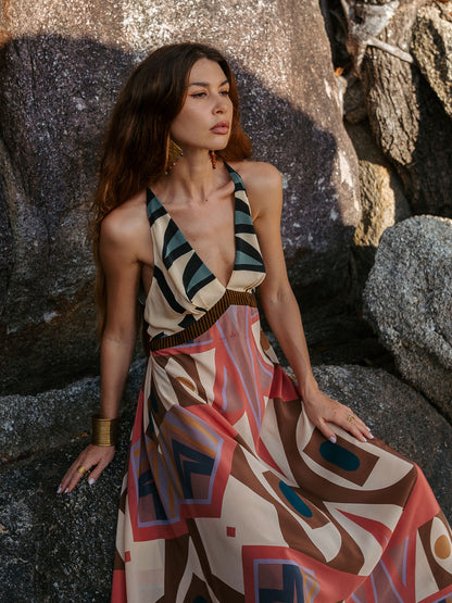 Woman in a patterned dress standing against a rocky background