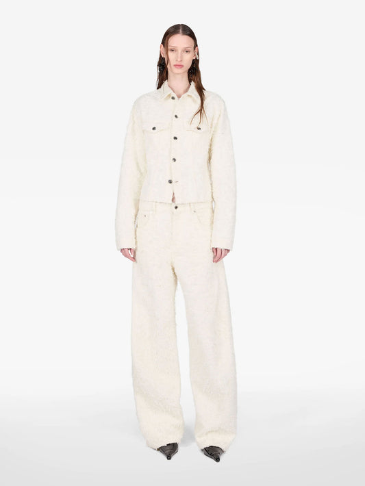 A model stands against a plain white studio background wearing a matching cream-colored textured jacket and wide-leg trousers set.