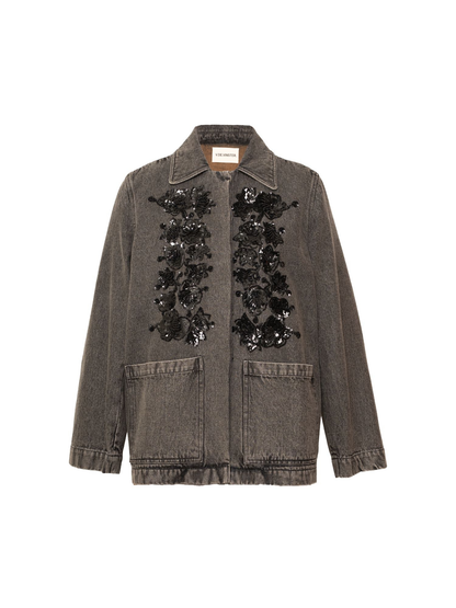 A washed charcoal gray denim jacket featuring black floral sequin embellishments on the front, a pointed collar, and two front patch pockets, shown against a plain white background.