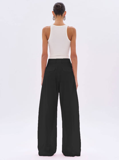 Person wearing a white sleeveless top and black wide-leg pants on a white background