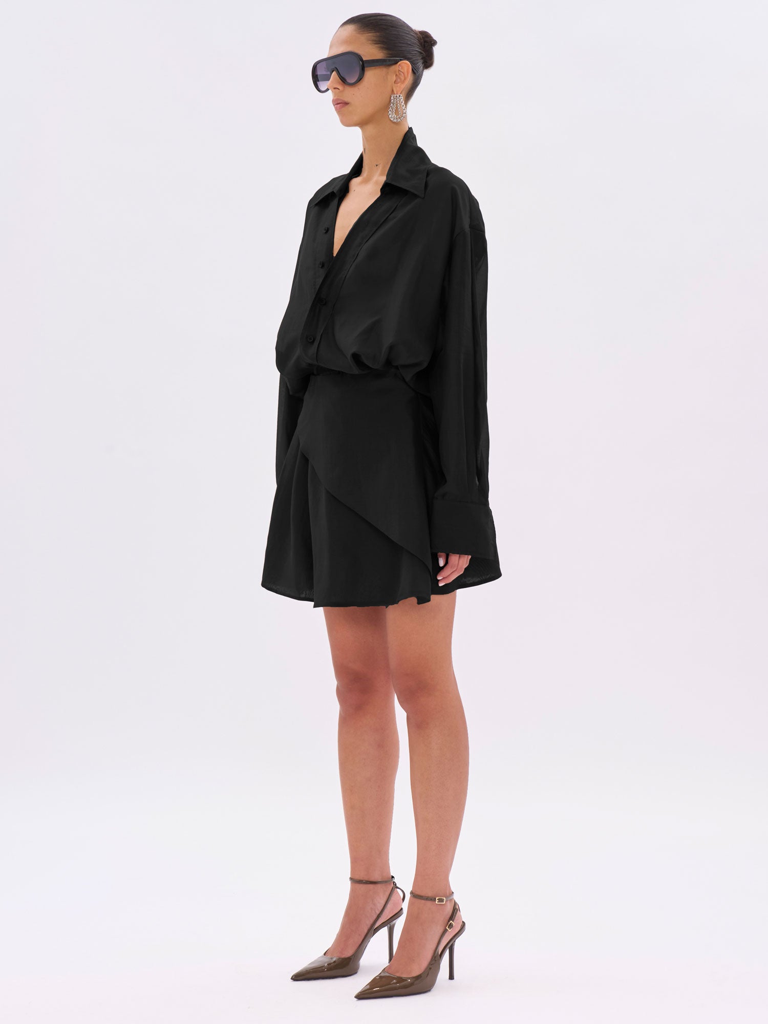 Woman wearing a black outfit with sunglasses on a white background