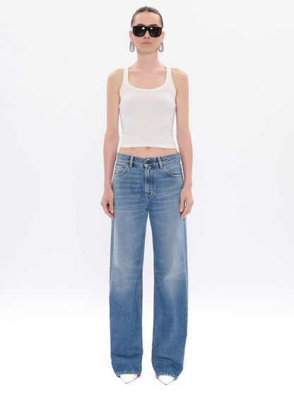 Woman wearing a white tank top and blue jeans on a white background