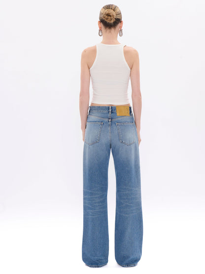 Person wearing blue jeans and a white top on a white background