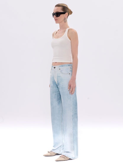 Woman wearing light blue jeans and a white tank top on a white background