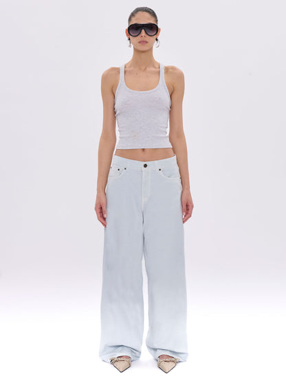 Woman wearing a white tank top and light blue jeans on a white background