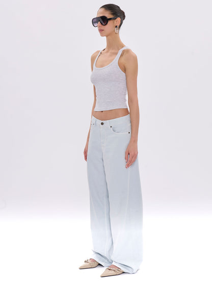 Woman wearing a white tank top and light blue jeans on a white background