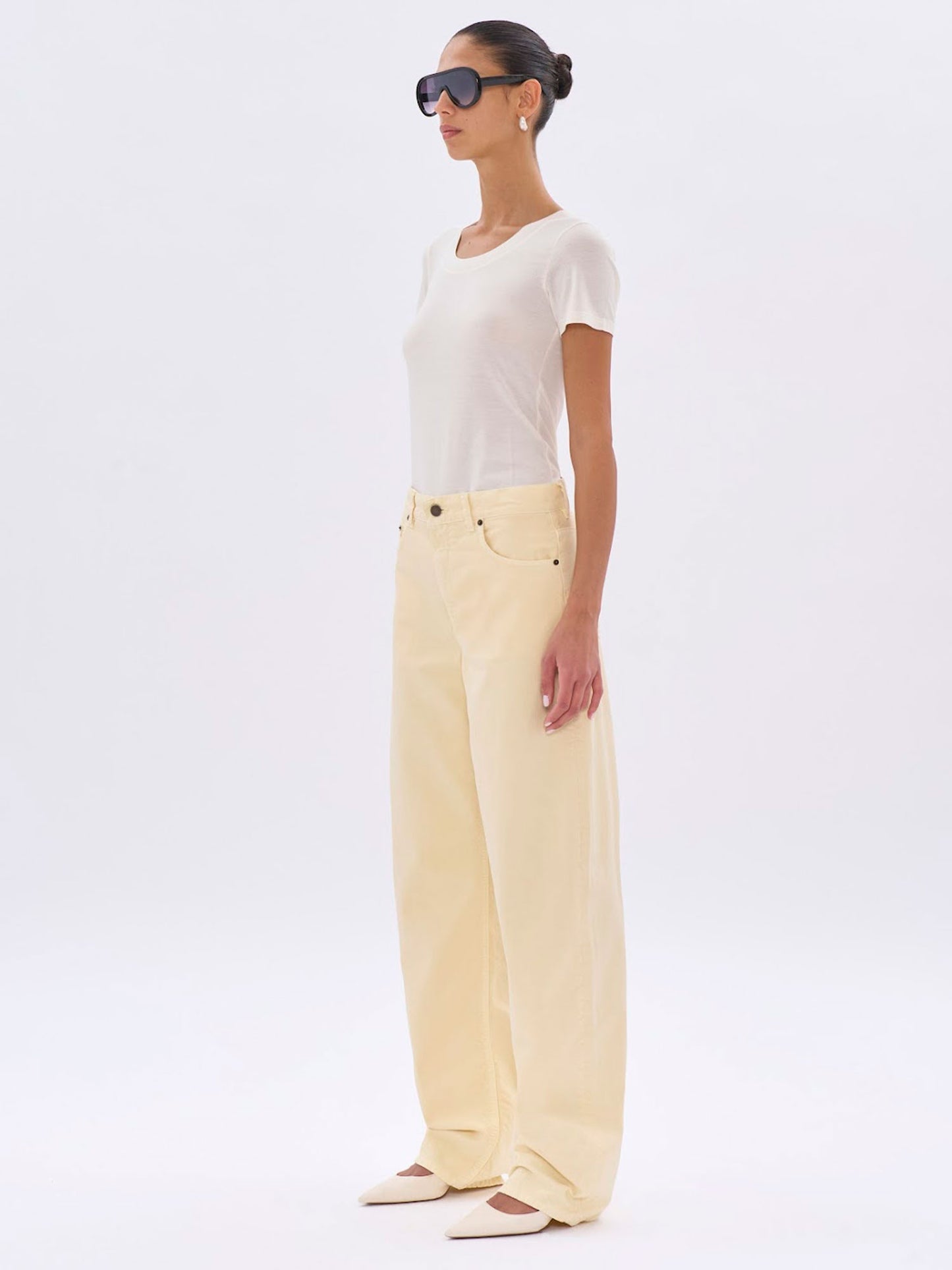 Woman wearing a white top and light yellow pants on a white background