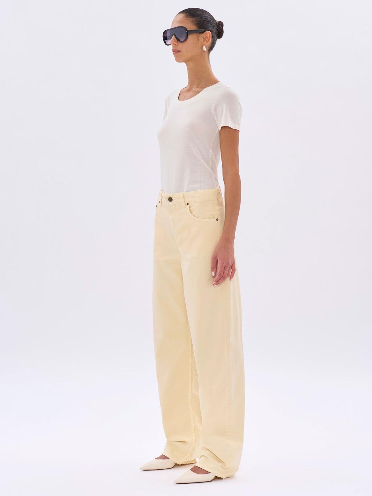 Woman wearing a white top and light yellow pants on a white background