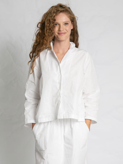 Woman wearing a white outfit against a plain background