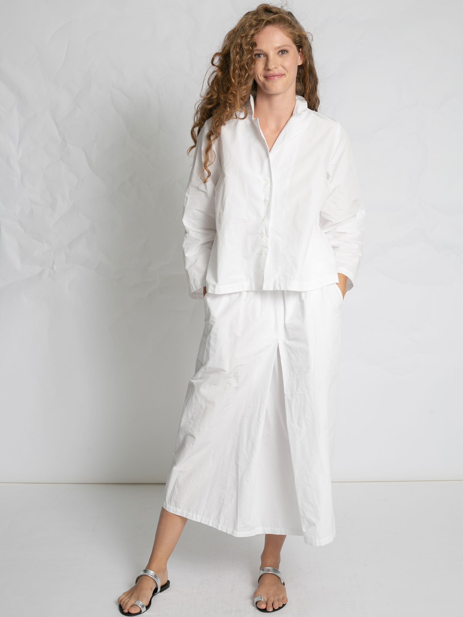 Woman wearing a white outfit against a plain background