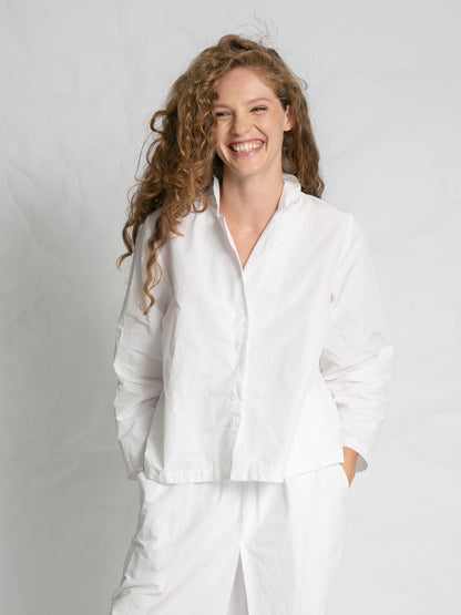 Woman wearing a white outfit against a plain background