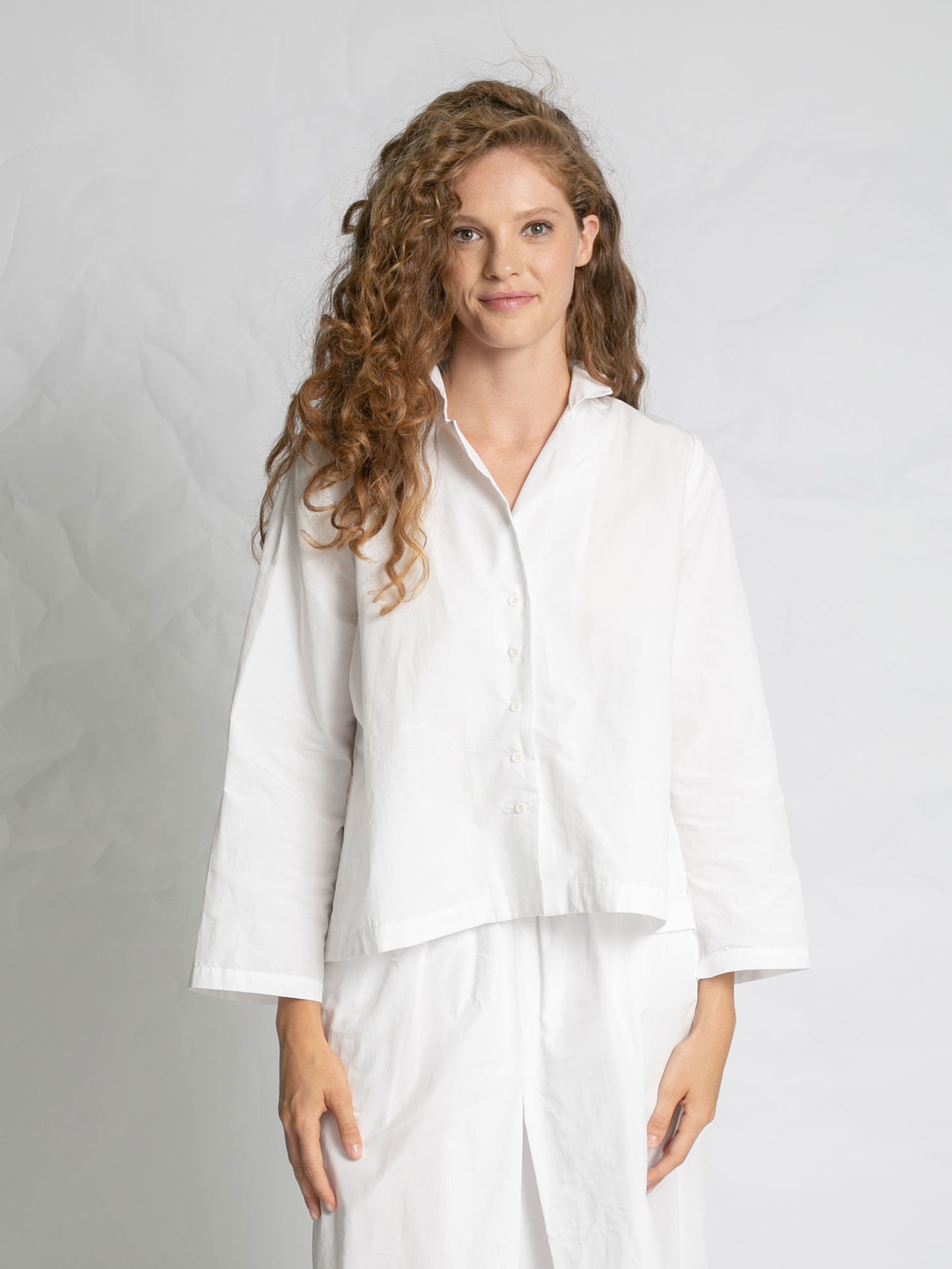 Woman wearing a white outfit against a plain background