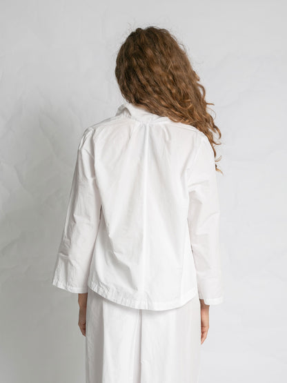 Person wearing a white jacket and pants against a plain background