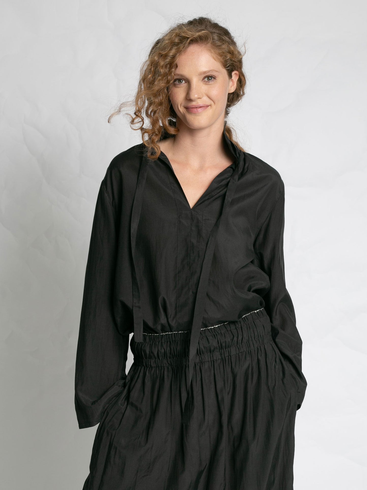 Woman wearing a black outfit against a plain background