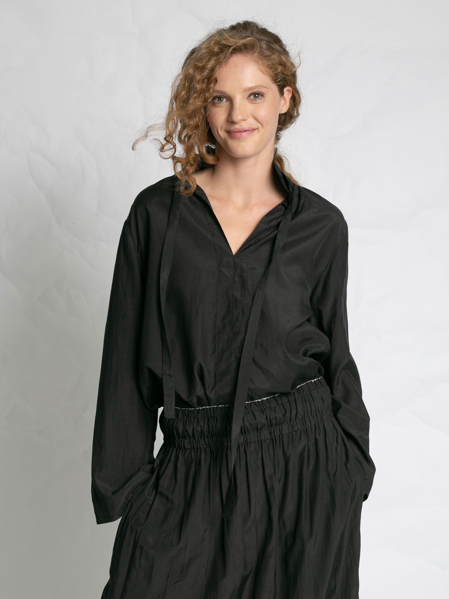 Woman wearing a black outfit against a plain background