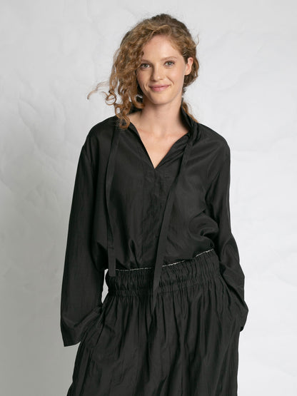 Woman wearing a black outfit against a plain background