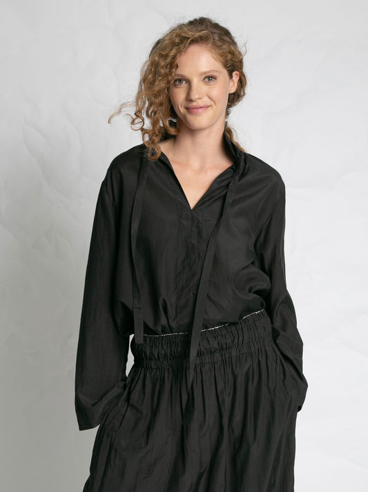 Woman wearing a black outfit against a plain background