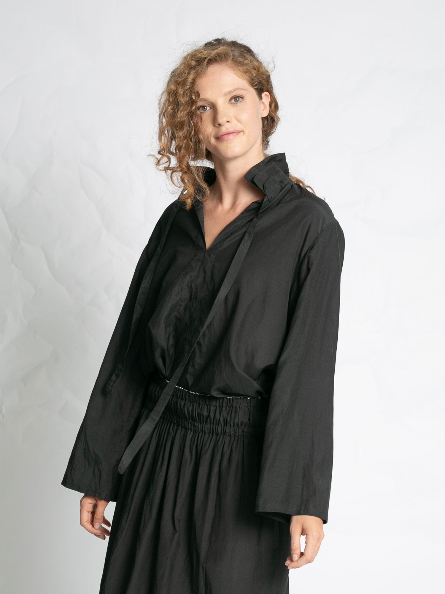 Woman wearing a black outfit against a plain background