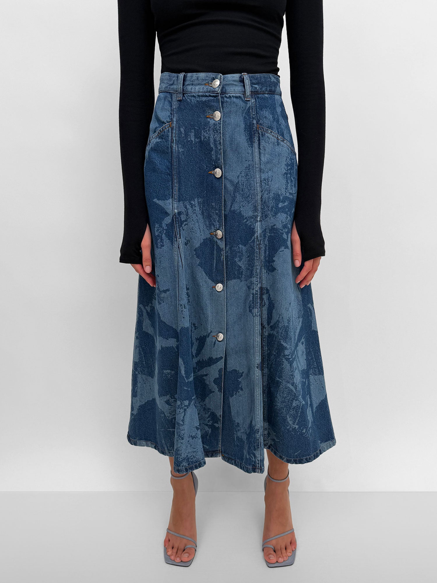 Blue denim skirt with button details worn by a person on a white background