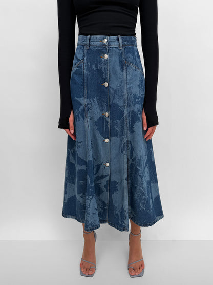 Blue denim skirt with button details worn by a person on a white background