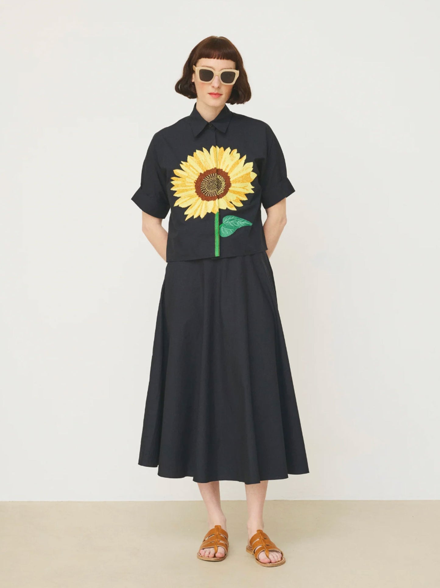 Person wearing a black Mii shirt with a sunflower design on a white background