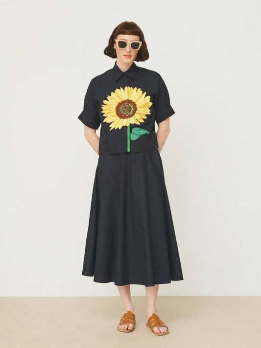 Person wearing a black Mii shirt with a sunflower design on a white background