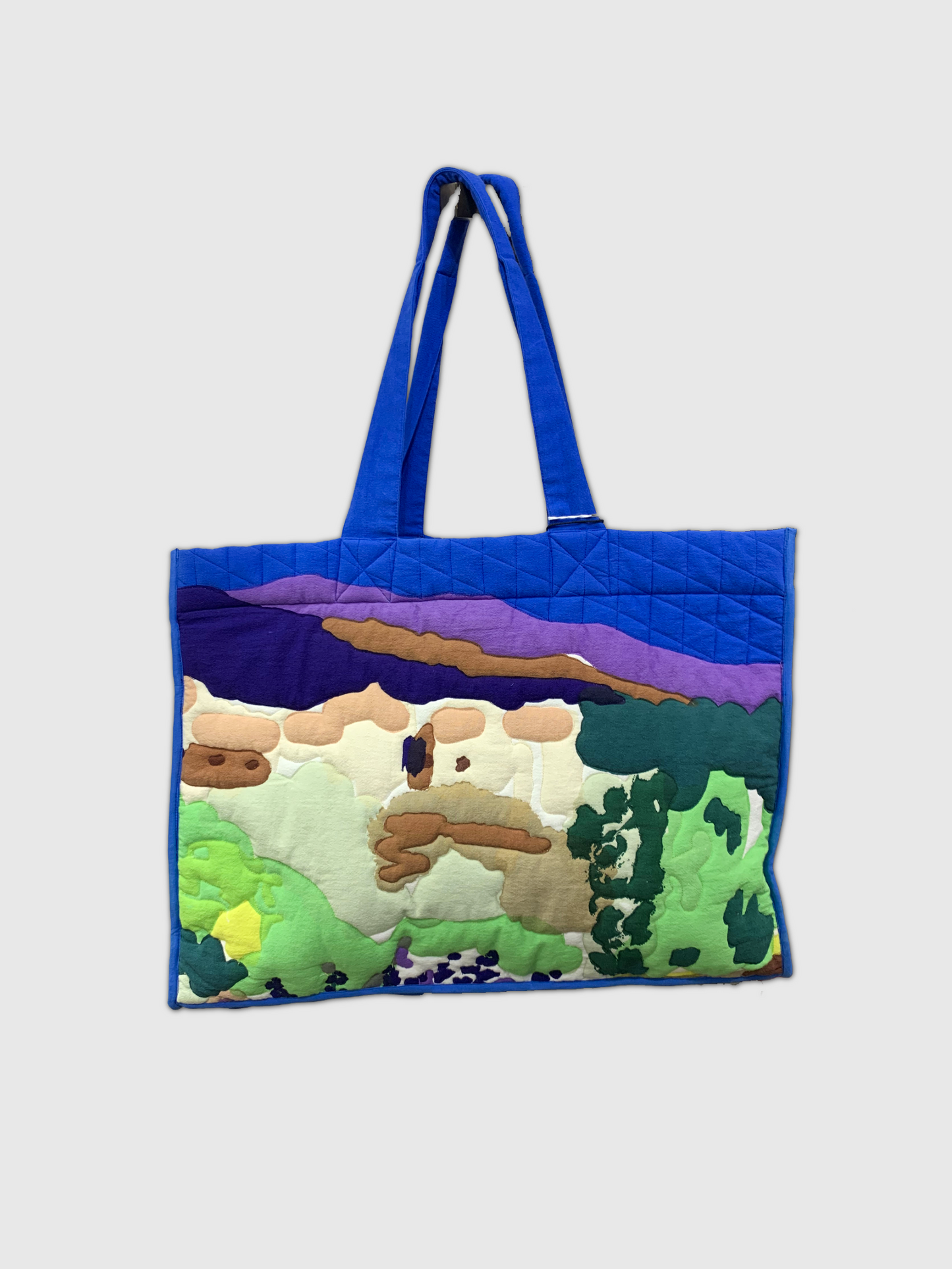 Tote bag with a landscape design featuring mountains and trees on a white background