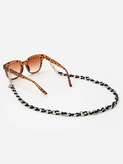 Sunglasses with a leopard print frame and chain strap on a white background