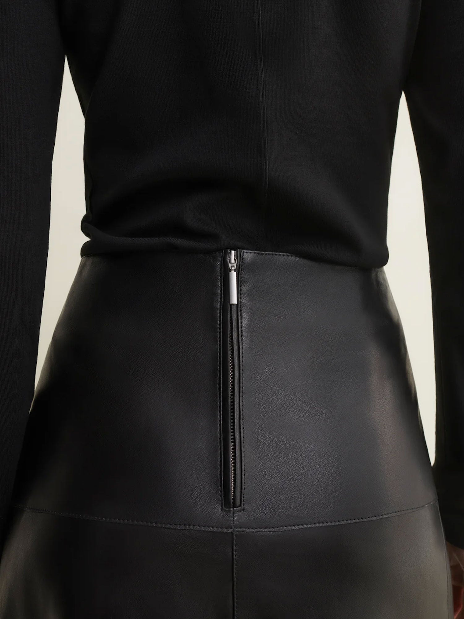 Black leather skirt with a zipper detail on a neutral background