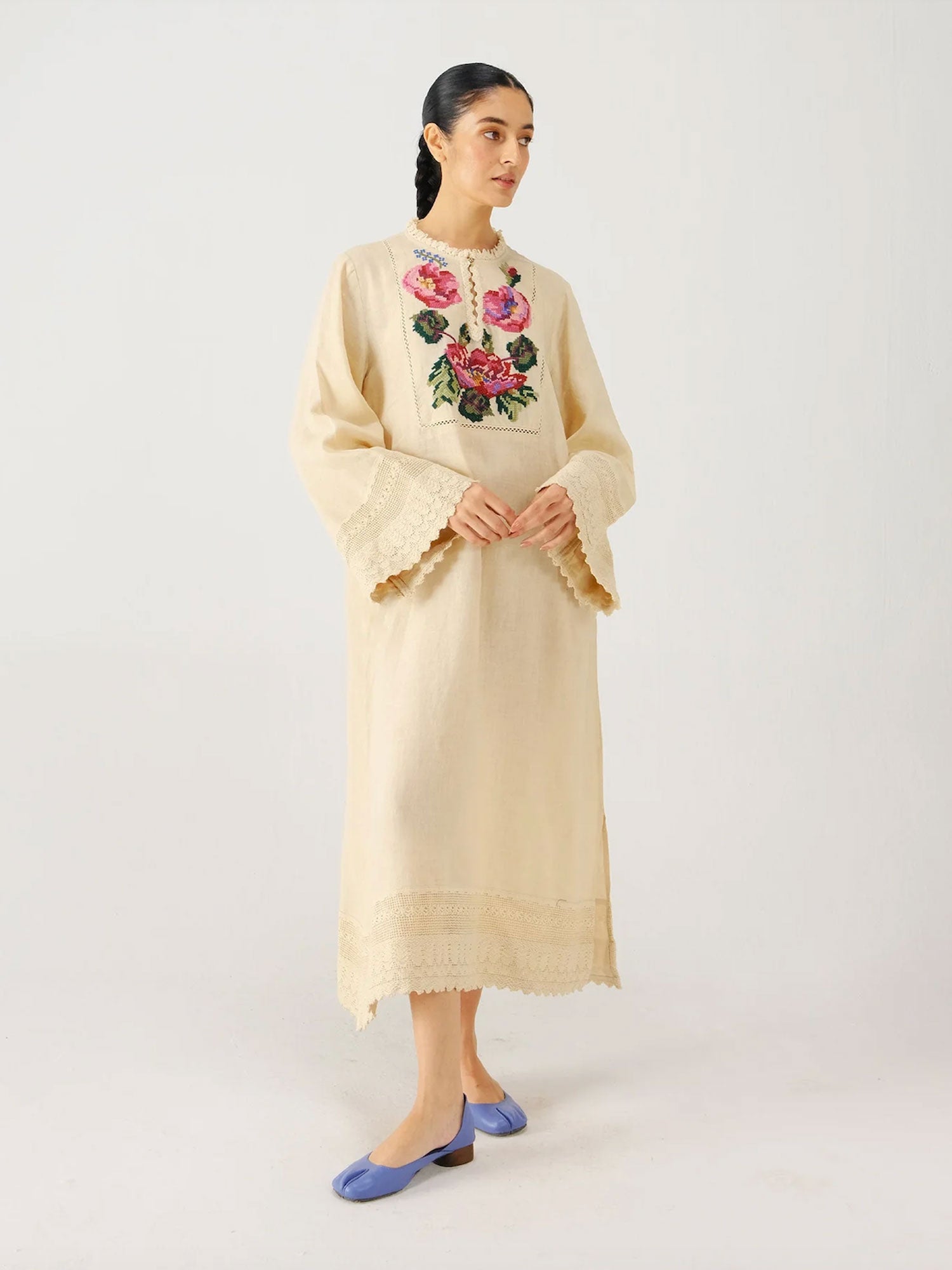 Woman wearing a beige embroidered dress on a white background