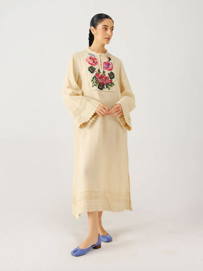 Woman wearing a beige embroidered dress on a white background