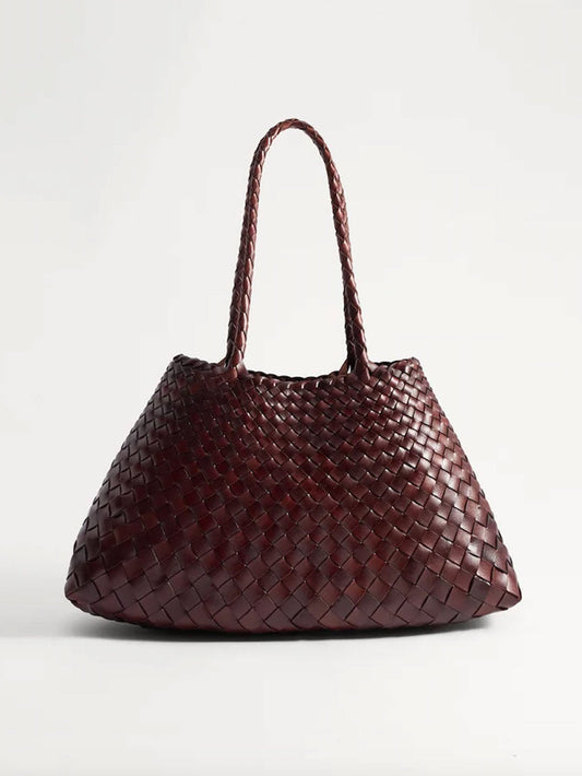 A dark burgundy woven leather handbag with two top handles, photographed against a clean, light gray studio background.