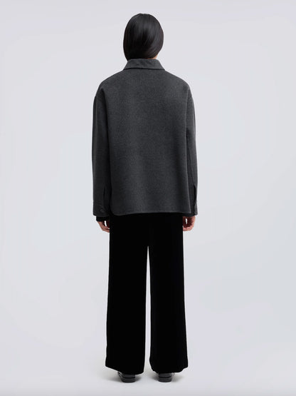 A model shown from the back wearing a dark gray long-sleeve knit top and black wide-leg trousers, photographed against a light gray studio background.