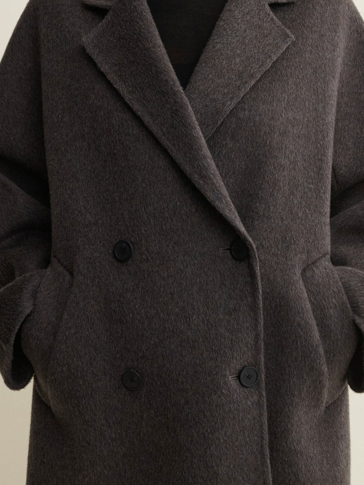 A close-up of a dark brown double-breasted wool coat with a soft, textured finish and black buttons.