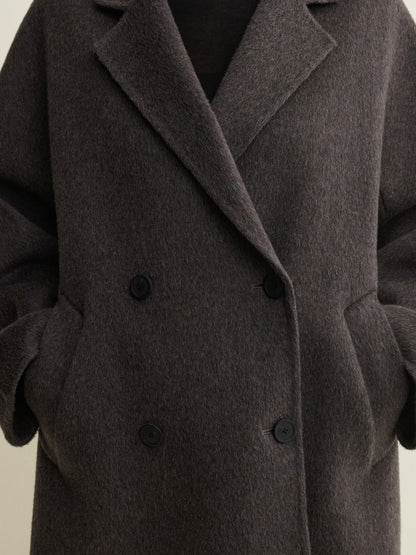 A close-up of a dark brown double-breasted wool coat with a soft, textured finish and black buttons.