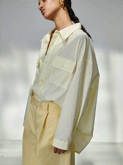 Woman wearing a light green shirt and beige pants against a neutral background