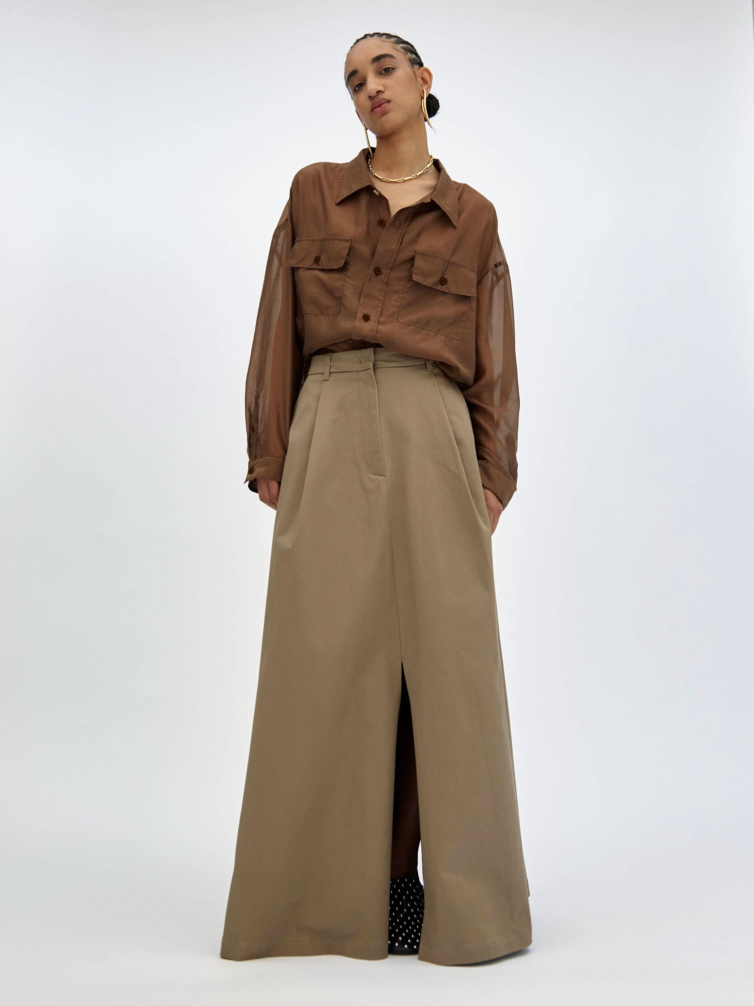 Person wearing a brown shirt and beige wide-leg pants on a white background