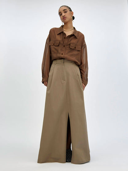 Person wearing a brown shirt and beige wide-leg pants on a white background