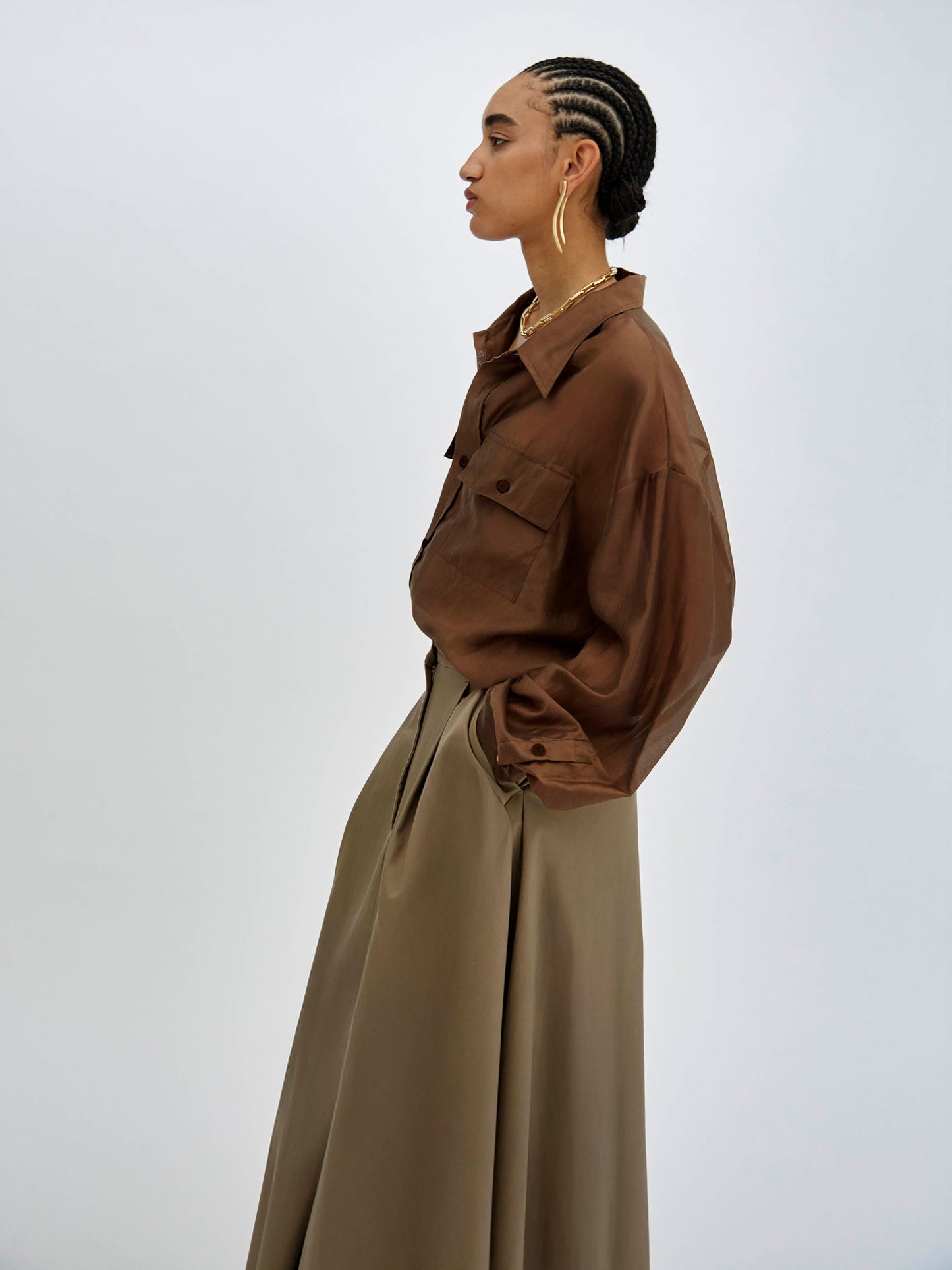 Woman wearing a brown shirt and beige skirt against a white background