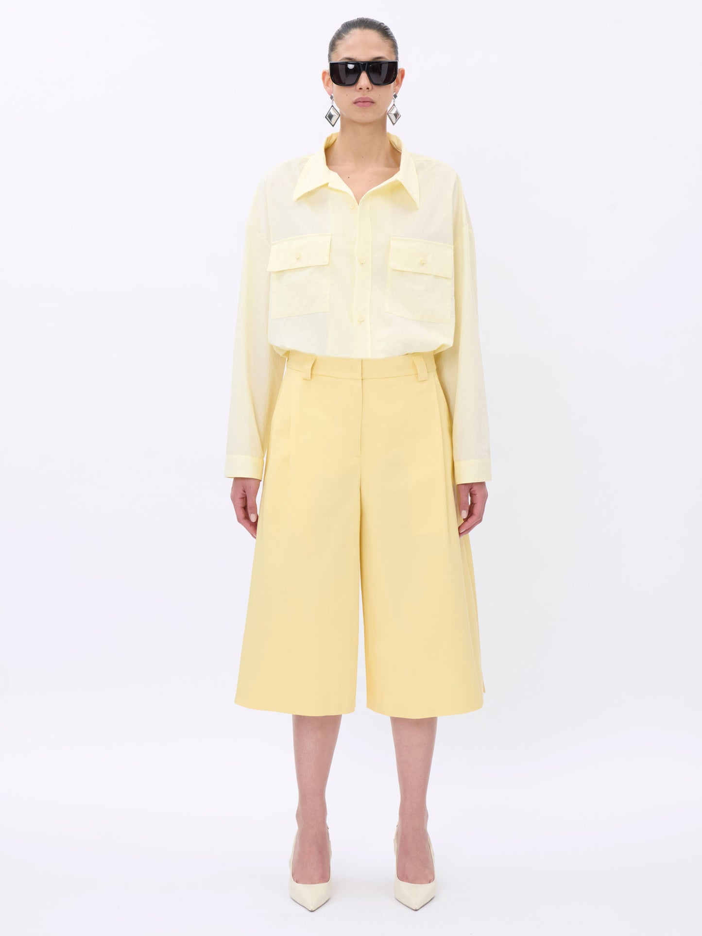 Person wearing a light yellow short with sunglasses on a white background